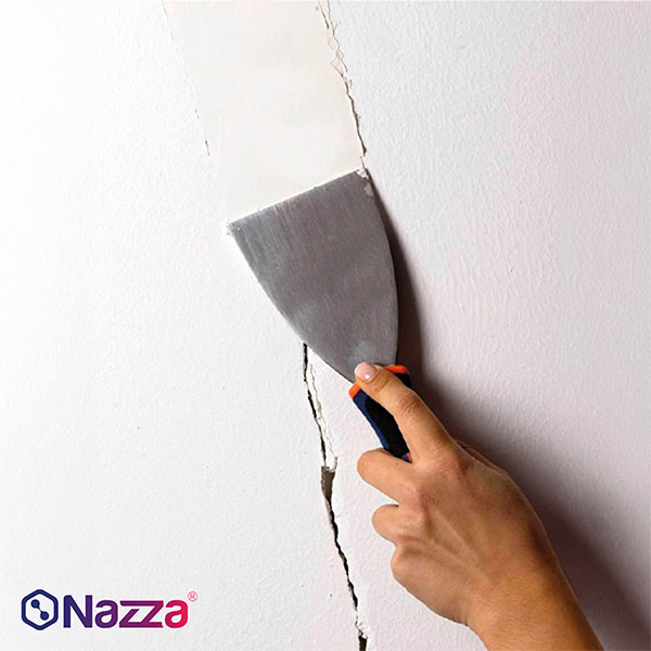 Reparación de una grieta en una pared mediante espátula, como parte de la preparación previa antes de aplicar la pintura.